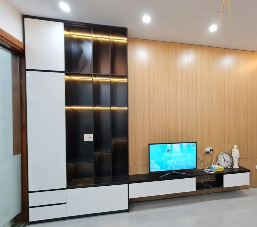 Ảnh thực tế – vách tivi ốp vân gỗ sáng, tủ hộc đen có đèn LED