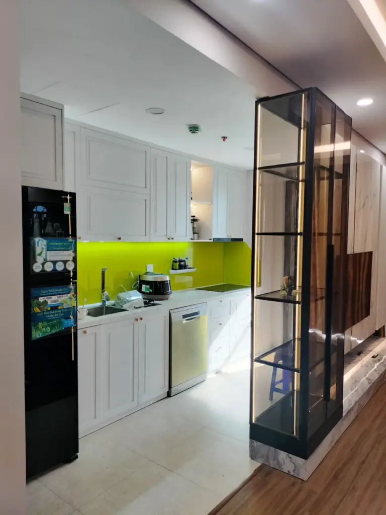 Bếp trắng cánh pano phào chỉ, kính ốp tường xanh cốm, kệ trưng bày khung đen kính có LED