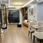 Phòng khách – phòng ăn liên thông, trần giật cấp LED hắt viền, đèn chùm pha lê, sàn gỗ vân sáng nối ra ban công