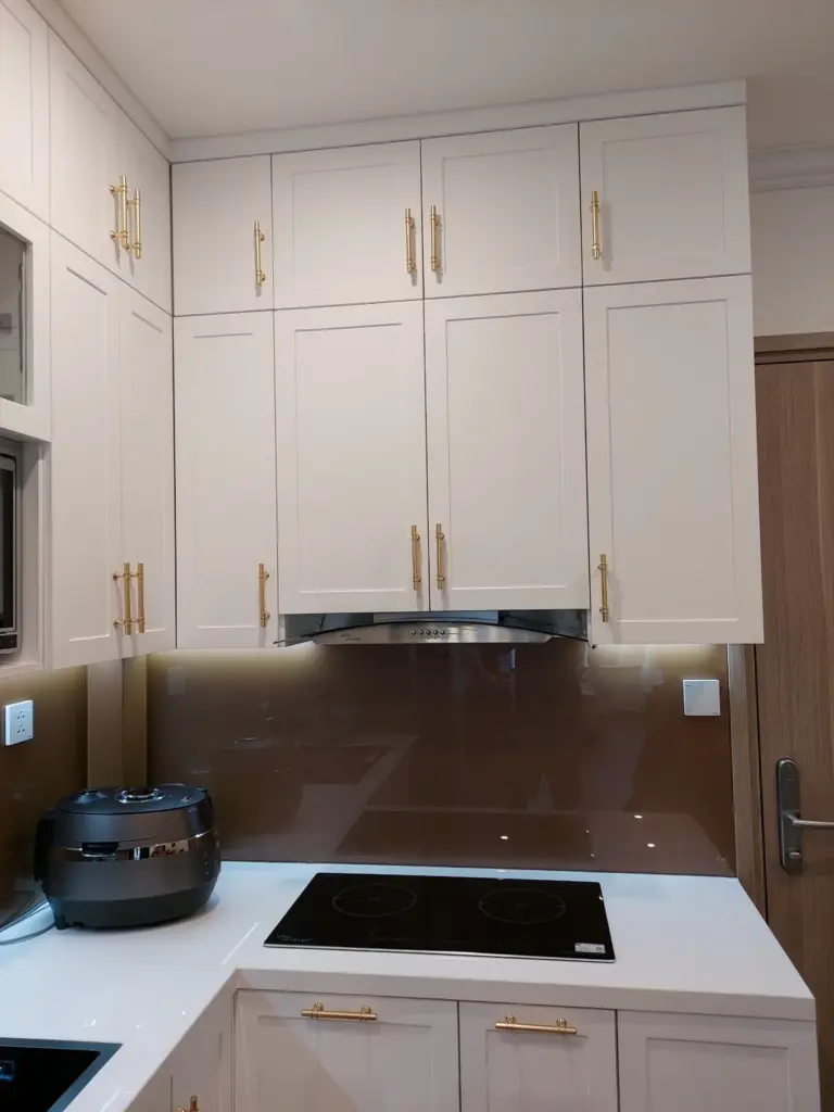 Ảnh thực tế – tủ bếp trên cánh chỉ, kính ốp tường màu đồng, đèn LED dưới tủ