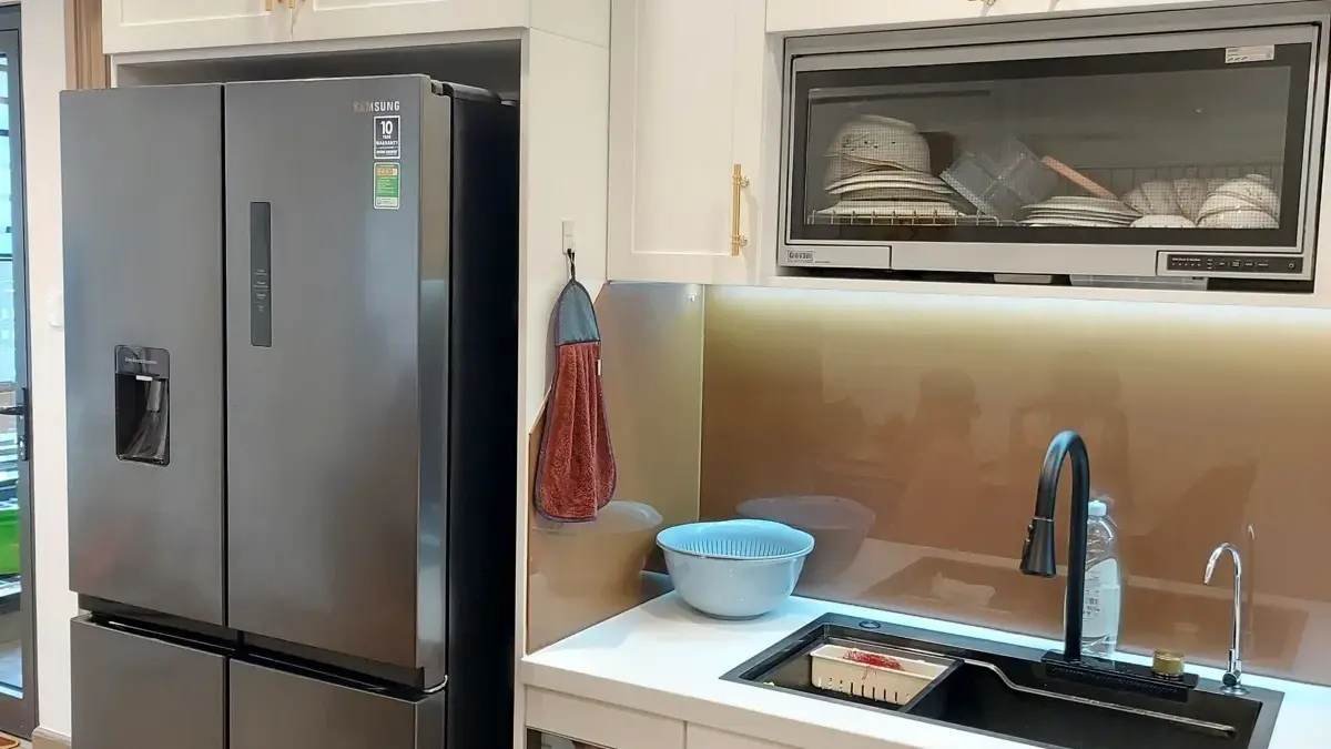 Ảnh thực tế – bếp tủ trắng tay nắm vàng đồng, giá bát nâng hạ, hốc tủ lạnh