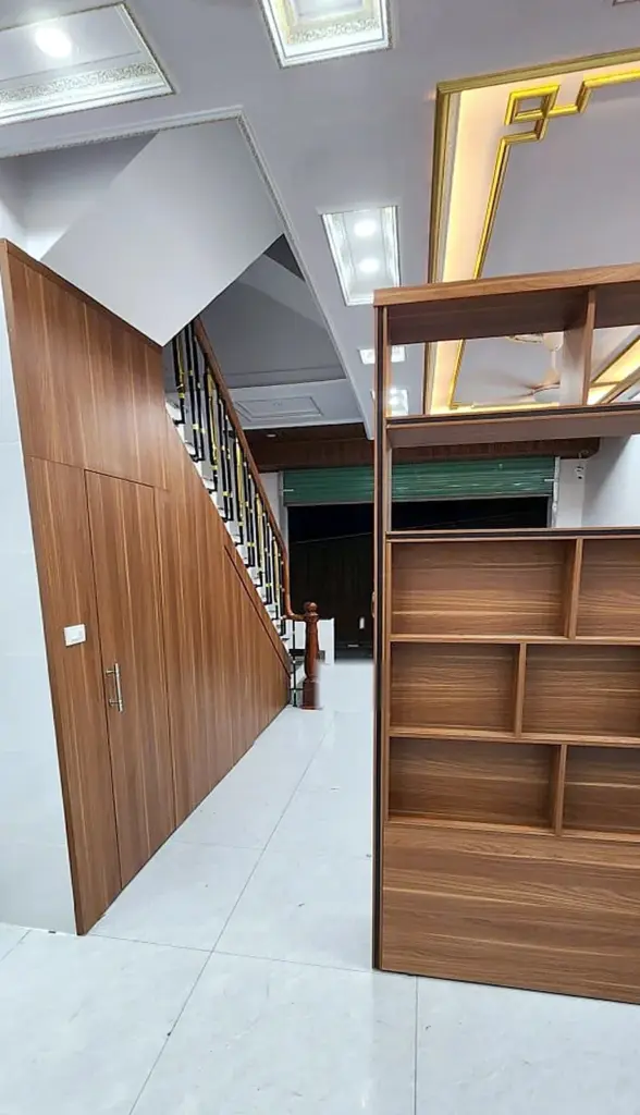 Ảnh thực tế – vách kệ gỗ ô so le ngăn phòng khách và bếp, bên trái là ốp gầm cầu thang
