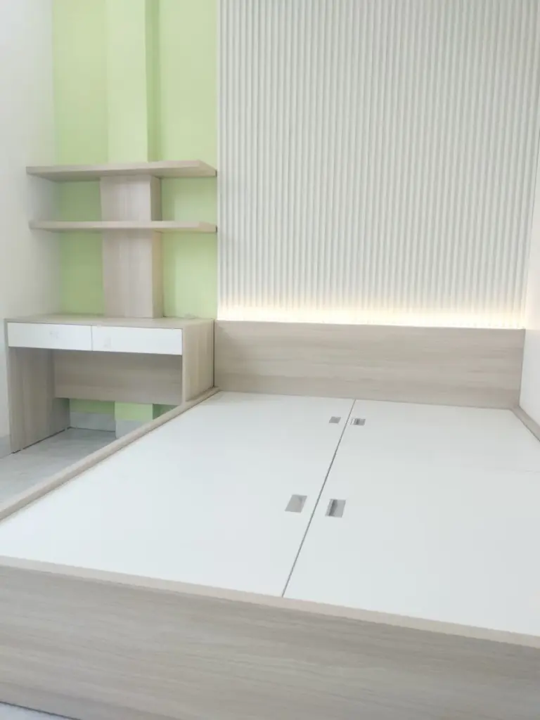 Ảnh thực tế – giường vân gỗ, đầu giường lam có đèn, bàn học và kệ treo
