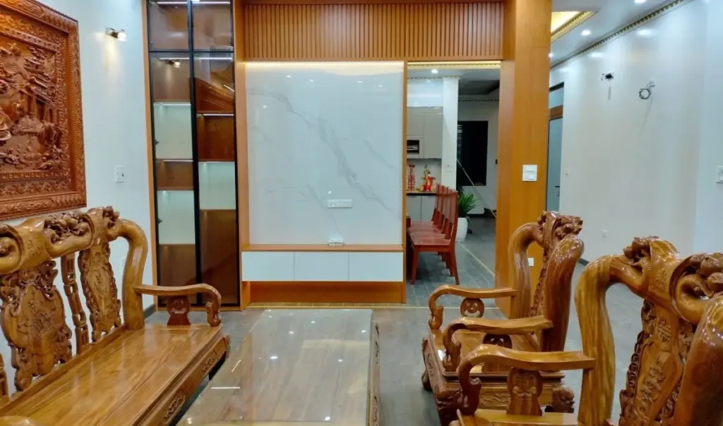 Ảnh thực tế – vách tivi ốp tấm vân đá trắng, lam gỗ và tủ trưng bày cánh kính có đèn