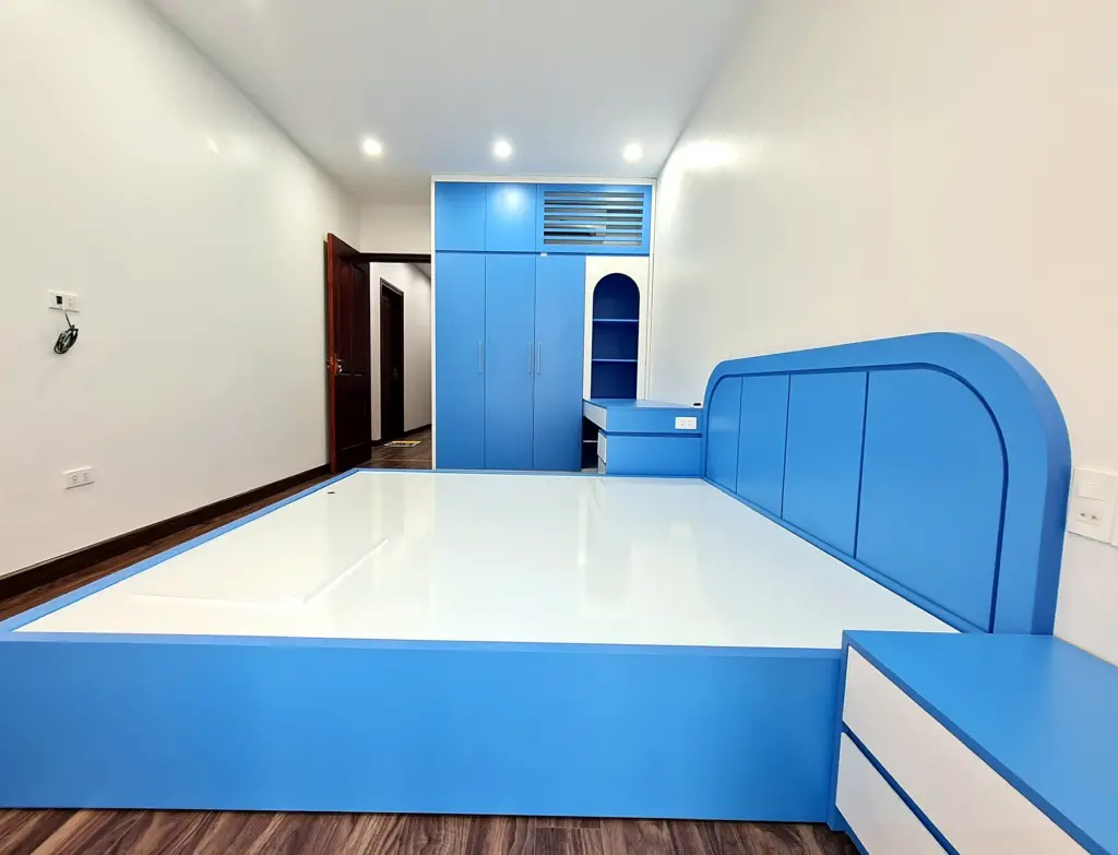 Ảnh thực tế – giường đầu bo tròn xanh dương, tab đầu giường hai ngăn kéo, tủ áo xanh và hốc kệ vòm cuối phòng