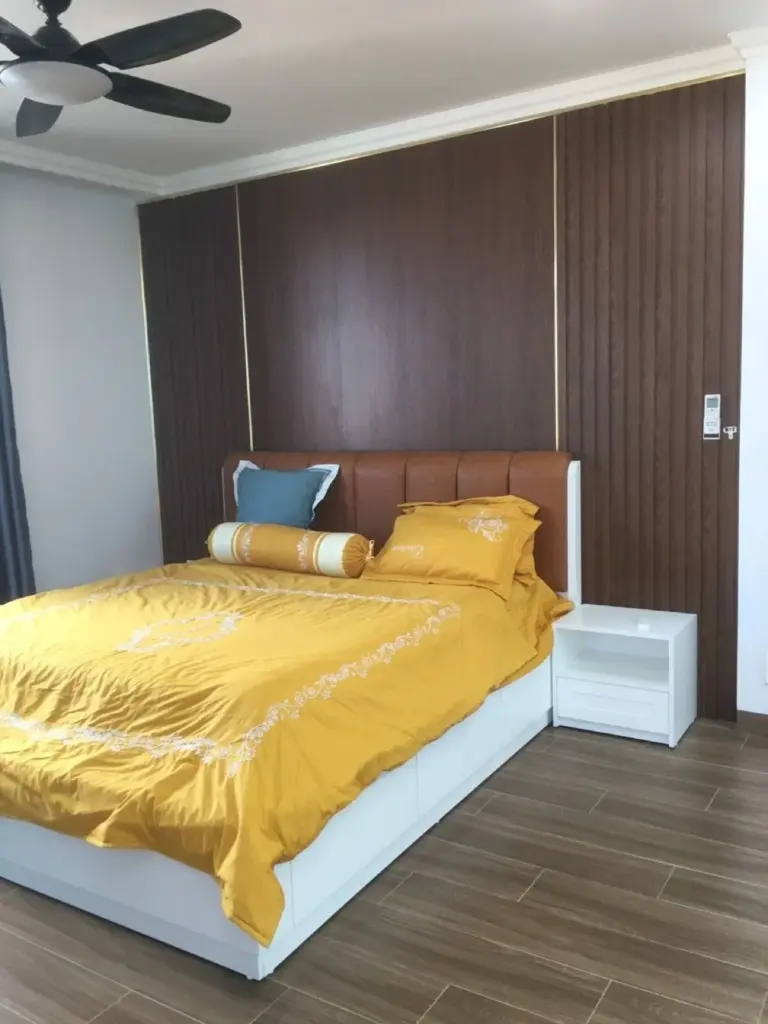 Ảnh thực tế – giường đầu bọc da, vách ốp gỗ tối