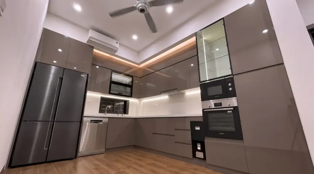 Ảnh thực tế – toàn cảnh bếp chữ L cánh nhựa phủ Acrylic nâu xám, cột lò âm tủ và tủ kính trưng bày