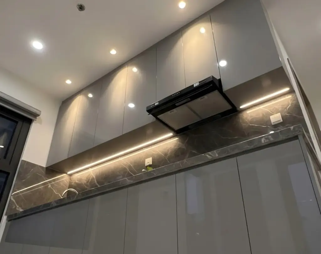 Ảnh thực tế – tủ bếp thùng inox 304, cánh acrylic xám bóng gương, tủ trên kịch trần, dải LED dưới tủ