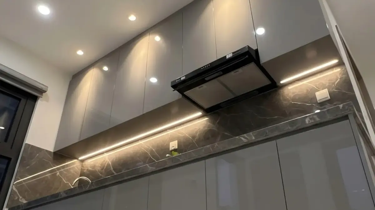 Ảnh thực tế – tủ bếp thùng inox 304, cánh acrylic xám bóng gương, tủ trên kịch trần, dải LED dưới tủ