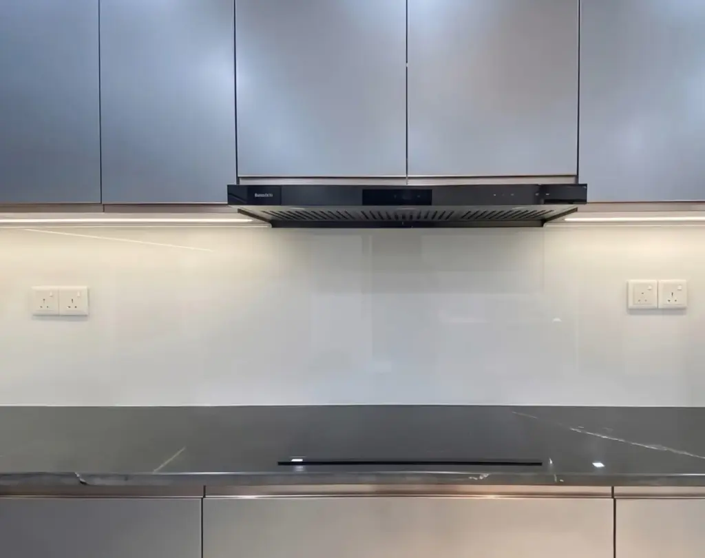 Ảnh thực tế – máy hút mùi âm dưới tủ trên, dải LED ấm, kính ốp tường trắng, mặt đá xám vân trắng
