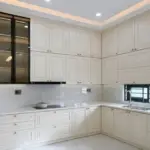 Ảnh thực tế – tủ bếp inox 304 chữ L tân cổ điển, cánh sơn trắng kem phào chỉ, tủ kính khung đen