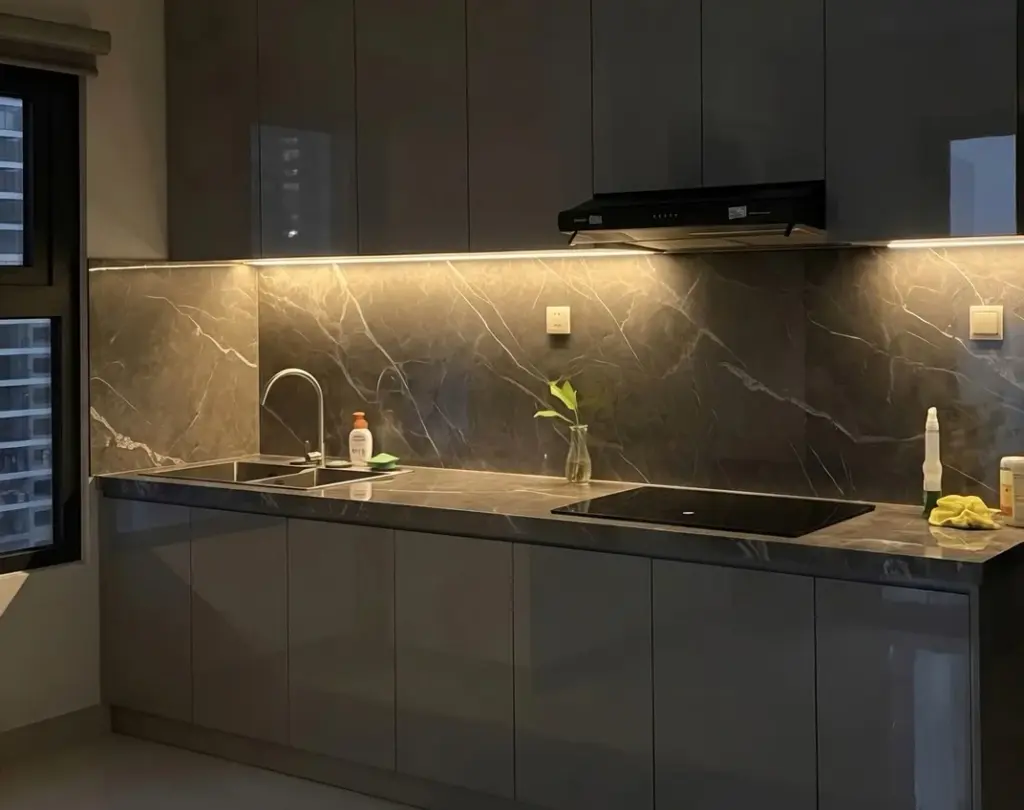 Ảnh thực tế – tủ dưới acrylic xám, đèn LED hắt dưới tủ trên, ốp đá tối màu
