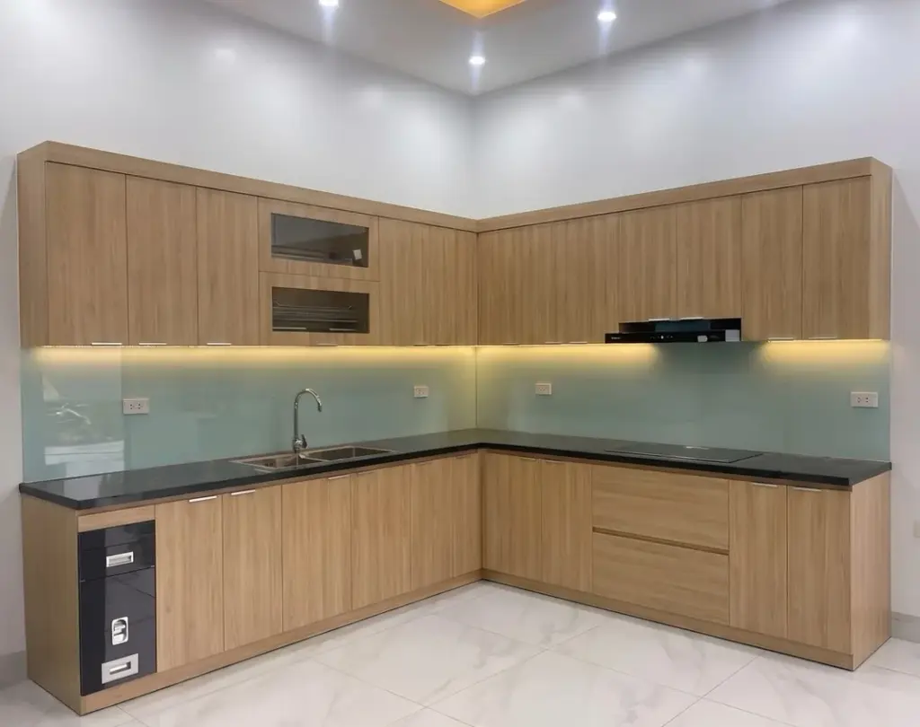 Ảnh thực tế – tủ bếp inox chữ L cánh MDF vân gỗ sáng, kính ốp xanh ngọc, nhà chị Xuân, Đống Đa