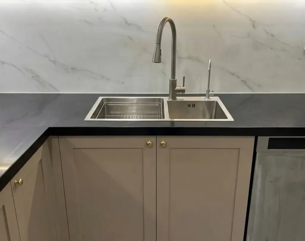Ảnh thực tế – chậu đôi inox trên mặt đá đen, tủ dưới cánh shaker ghi núm đồng