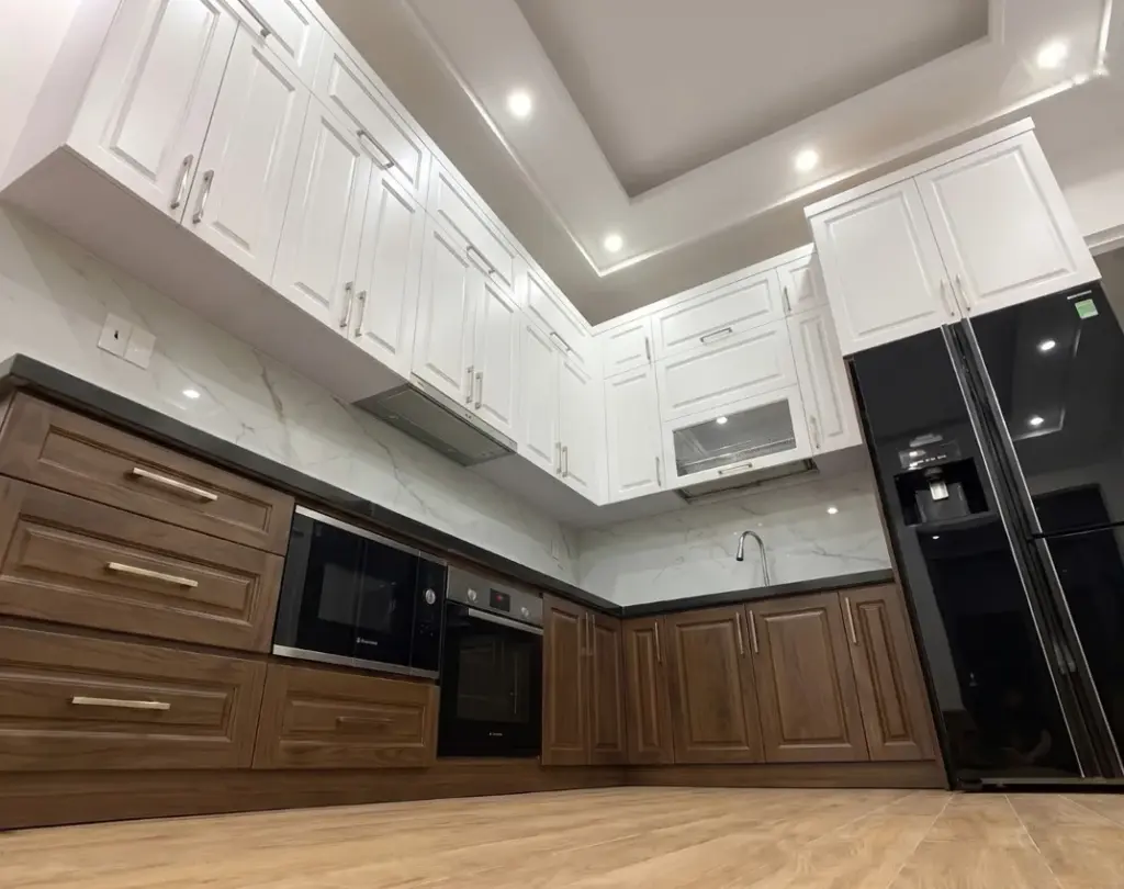 Ảnh thực tế – góc chữ L, mặt đá đen, tủ dưới nâu gỗ ngăn kéo pano, nhà chị Dung